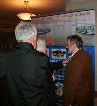 Thierry Chopin explaining the IMTA banner to Betty Tompkins, from the art side (New Brunswick Arts Council), and Carl Tompkins, from the science side (former Dean of Science at the University of New Brunswick in Saint John).
